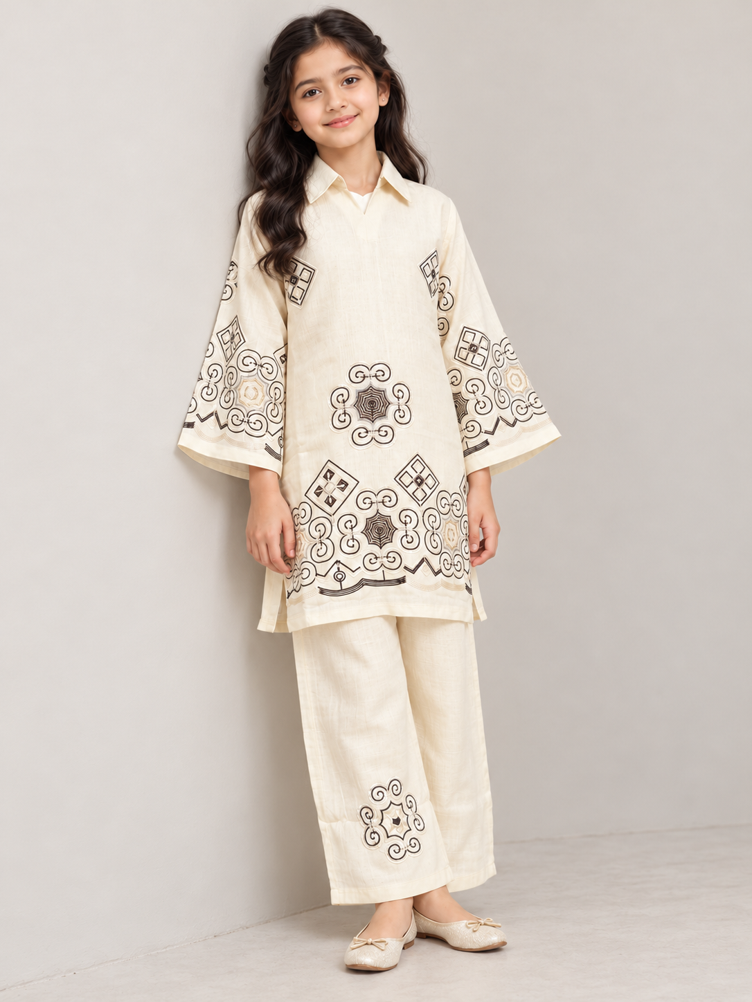 Model wearing the cream cotton embroidery kurti set, standing by a wall